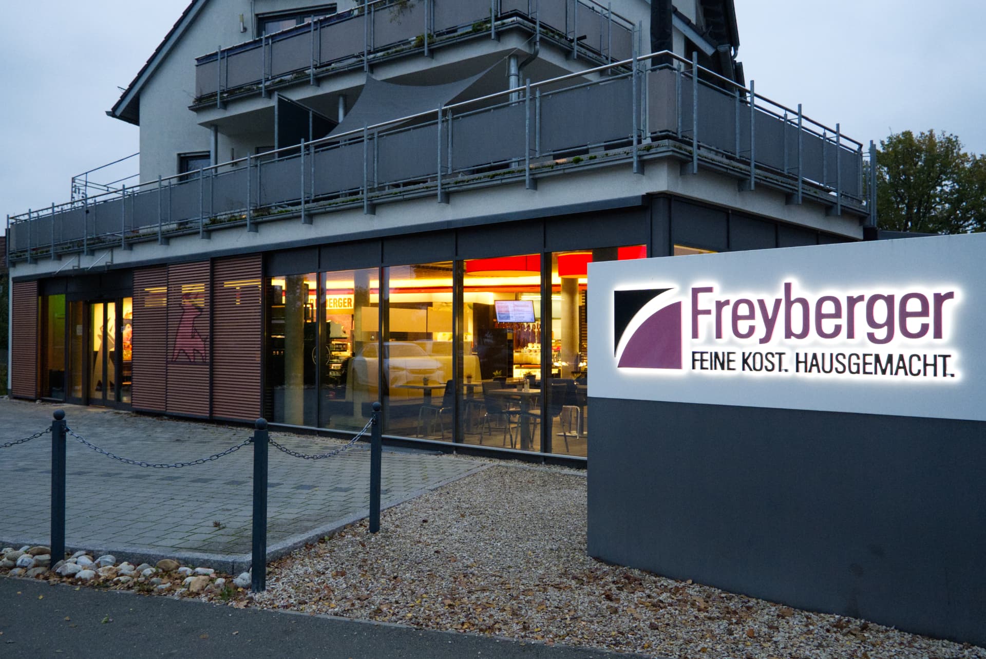 Beleuchtete Ladenfront der Metzgerei Freyberger in der Abenddämmerung