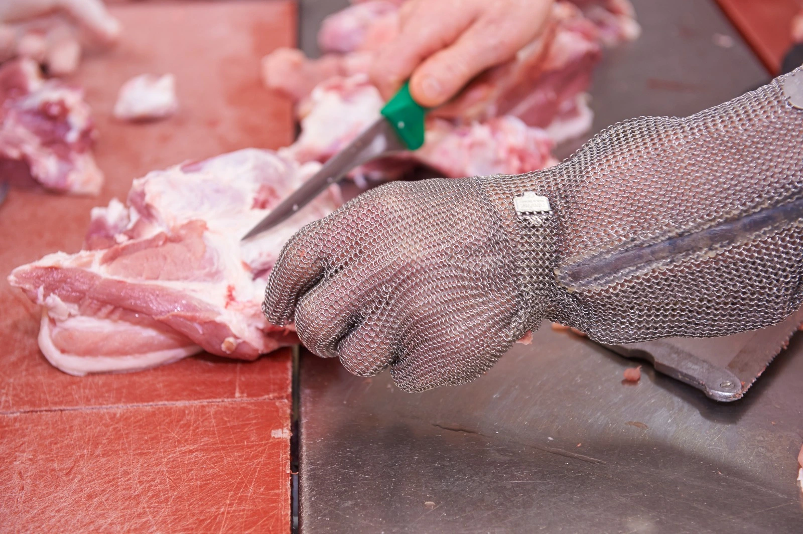 Fleischer beim Ausbeinen mit Kettenhandschuh